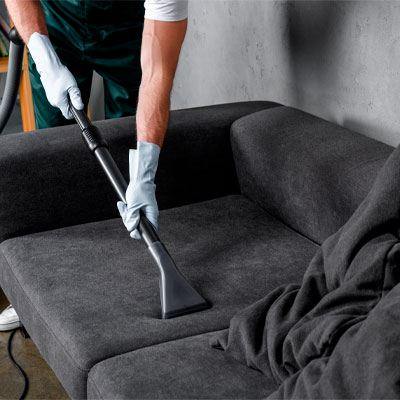 Profissional higienizando sofá escuro com extratora